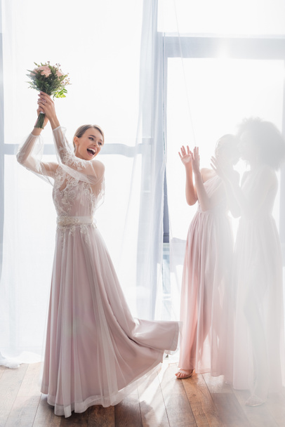 excited bride throwing wedding bouquet near bridesmaids - Photo, Image