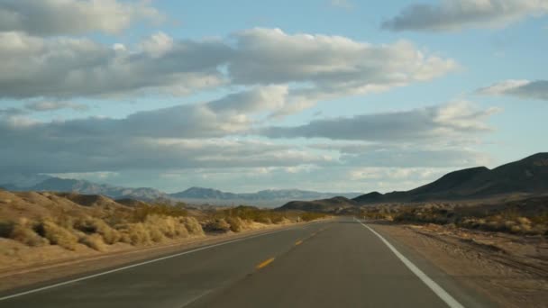 Viaggio in auto dalla Death Valley a Las Vegas, Nevada, USA. Autostop in viaggio in America. Viaggio in autostrada, atmosfera drammatica, montagna al tramonto e deserto del Mojave. Vista dalla macchina - Filmati, video