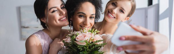 happy african american woman taking selfie with wedding bouquet and friends, blurred foreground, banner - Photo, Image