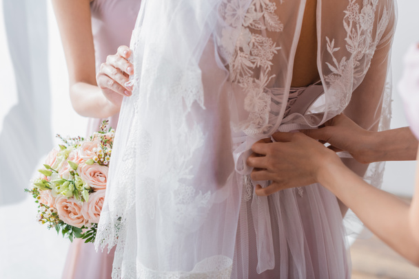 cropped view of bridesmaids preparing bride for wedding - Photo, Image