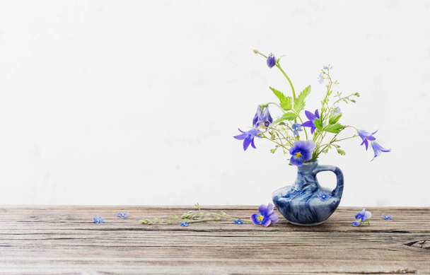 summer flowers in blue jug on old wooden table - Foto, Imagen