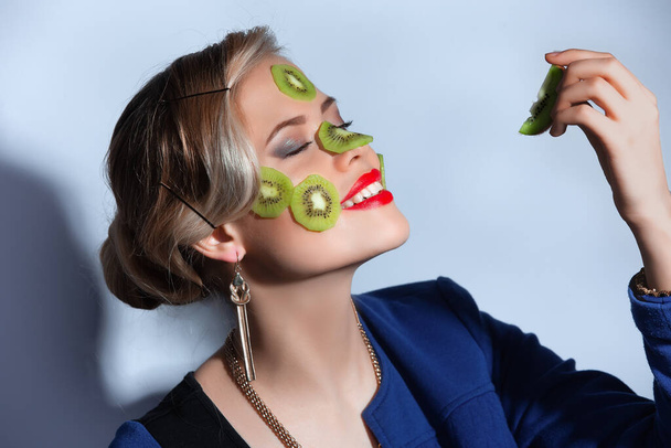 Fashion photo of woman posing with slices of kiwi on her face - Foto, imagen