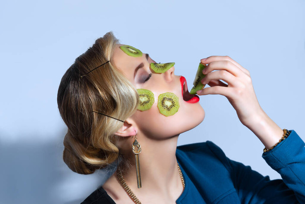 Fashion photo of woman posing with slices of kiwi on her face - Foto, Imagen