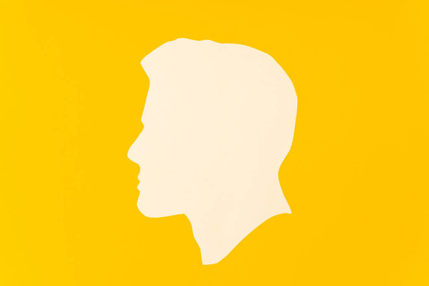 Προφίλ ενός ανθρώπου κομμένο κεφάλι και χαρτί σε κίτρινο φόντο - Φωτογραφία, εικόνα