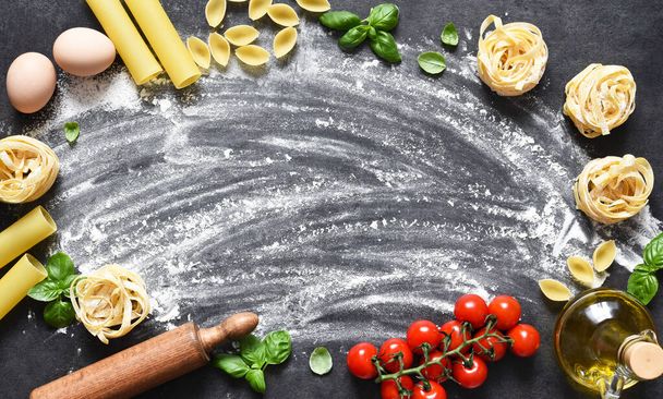 Flour, rolling pin, tomatoes and basil on the table. Pasta cooking process on the kitchen table. Ingredients for making pasta. - Φωτογραφία, εικόνα