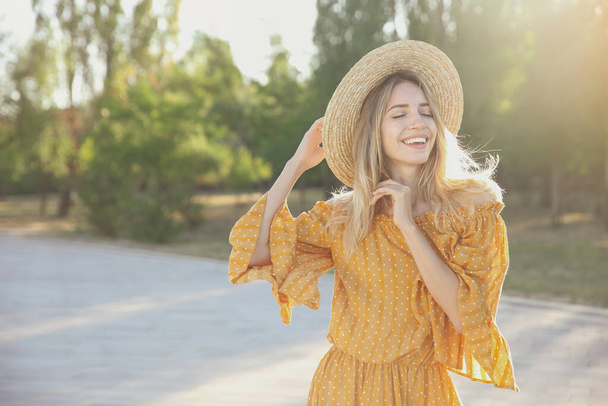 Beautiful young woman in stylish yellow dress and straw hat outdoors - Fotografie, Obrázek