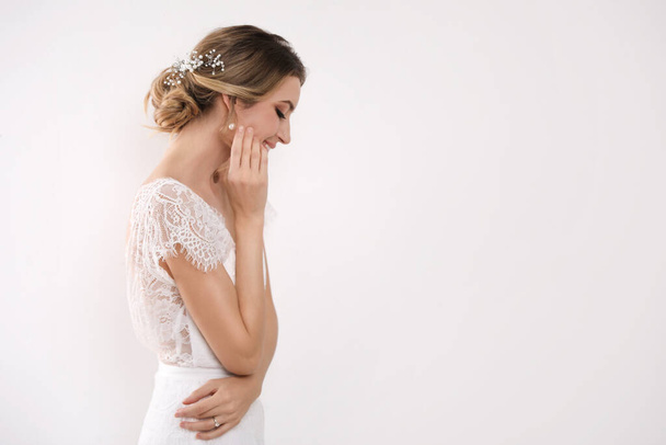 Young bride with elegant wedding hairstyle on light background. Space for text - Foto, immagini
