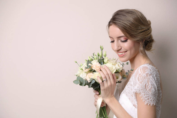 Young bride with beautiful wedding bouquet on beige background. Space for text - Foto, immagini