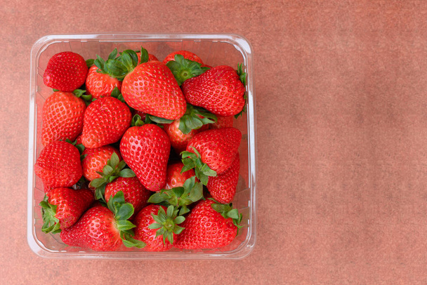 Bowl full of strawberries on brown background - Photo, Image