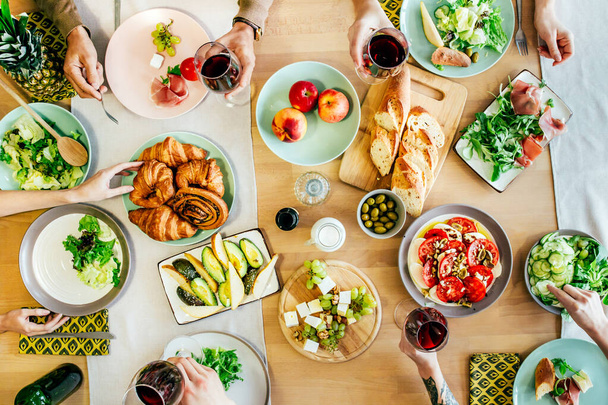 vue de dessus de la fête des personnes à la table couverte de nourriture et de boissons avec des plats, salades, fruits, légumes, vin et sauces - Photo, image