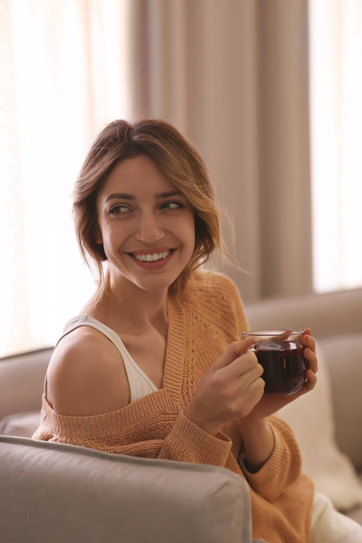 Beautiful young woman with cup of tea relaxing at home. Cozy atmosphere - Fotografie, Obrázek