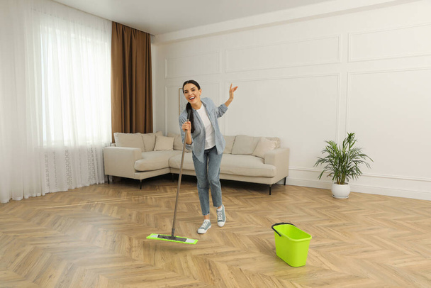 Frau hat Spaß beim Fußbodenputzen mit Wischmopp - Foto, Bild