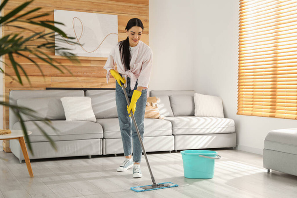 Mujer limpiando piso con fregona en casa - Foto, imagen