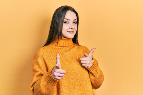Jong Latijns-Amerikaans meisje draagt casual kleding wijzende vingers naar camera met een vrolijk en grappig gezicht. goede energie en vibes.  - Foto, afbeelding