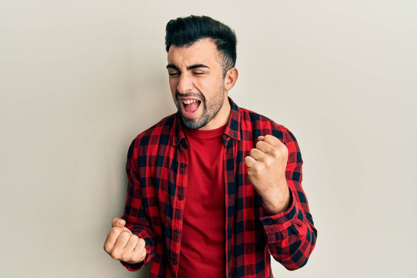 Young hispanic man wearing casual clothes celebrating surprised and amazed for success with arms raised and eyes closed  - Φωτογραφία, εικόνα