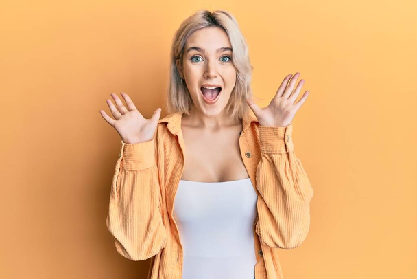 Young blonde girl wearing casual clothes celebrating crazy and amazed for success with arms raised and open eyes screaming excited. winner concept  - Fotoğraf, Görsel