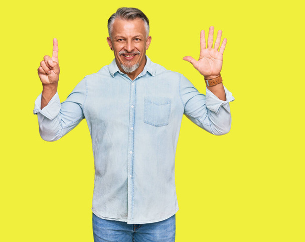 Hombre de pelo gris de mediana edad vistiendo ropa casual mostrando y señalando con los dedos número seis mientras sonríe confiado y feliz.  - Foto, imagen