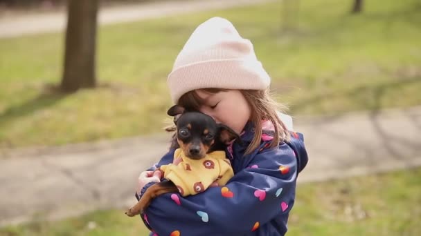 Gyönyörű kislány séta aranyos kutya a szabadban. Hat éves kislány megöleli a kisállatát. - Felvétel, videó