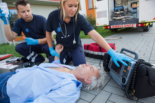 Paramedics checking pulse of man - Foto, afbeelding