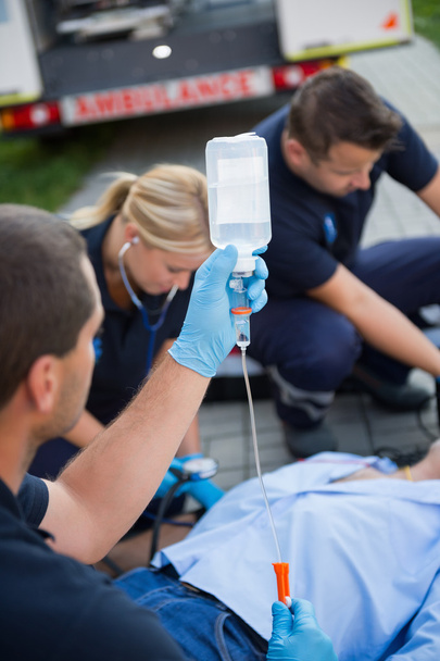 Paramedic team preparing drip for patient - Foto, afbeelding