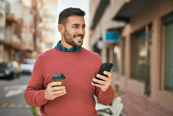 Młody Hiszpan korzystający ze smartfona i pijący kawę w mieście. - Zdjęcie, obraz