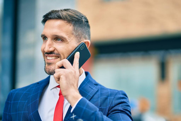 Giovane uomo d'affari caucasico sorridente felice parlando sullo smartphone in città. - Foto, immagini