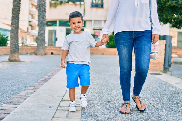 Αξιολάτρευτη Λατίνα μητέρα και γιος περπατούν στην πόλη. - Φωτογραφία, εικόνα