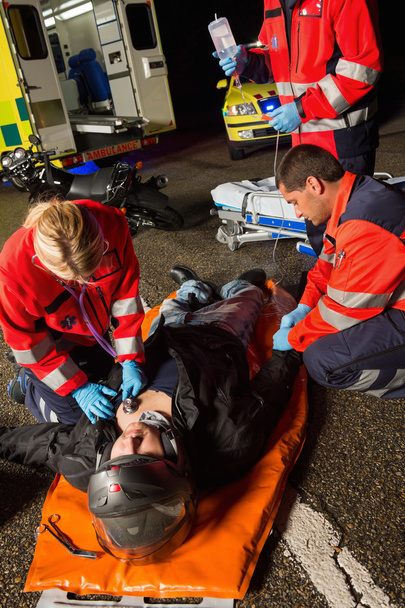 Paramedics examining injured motorcycle driver - Foto, Bild
