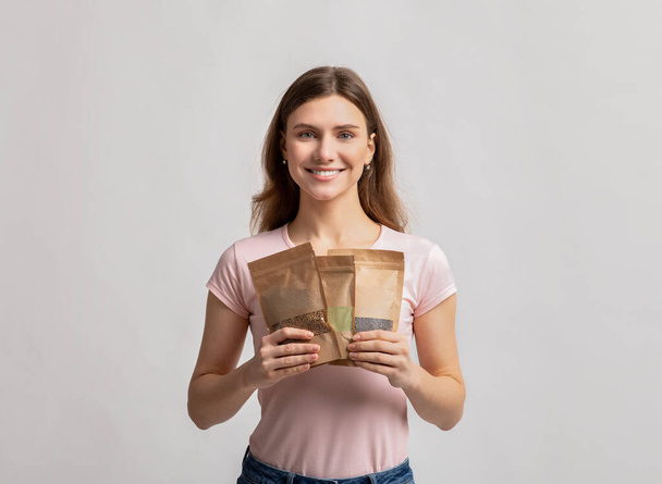 Öko-raktározási koncepció. Mosolygó Y-generációs hölgy kezében doypack táskák súly élelmiszereket - Fotó, kép