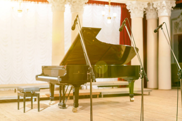 Klavír v koncertní síni. Klavír stojí na prázdném pódiu. otevřený černý klavír se stoličkou na dřevěném pódiu. tónovaný - Fotografie, Obrázek