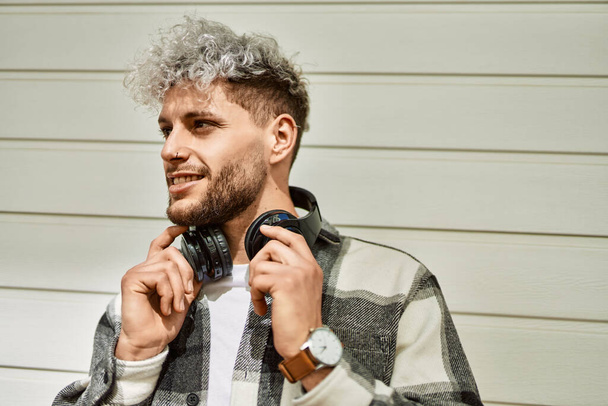 Joven hombre hispano sonriendo feliz usando auriculares en la ciudad. - Foto, Imagen