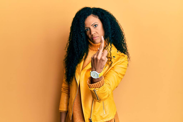 Middle age african american woman wearing wool winter sweater and leather jacket showing middle finger, impolite and rude fuck off expression  - Foto, imagen