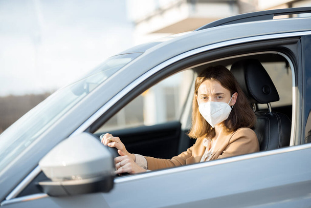 Mujer conduciendo coche con máscara protectora en su cara.  - Foto, imagen