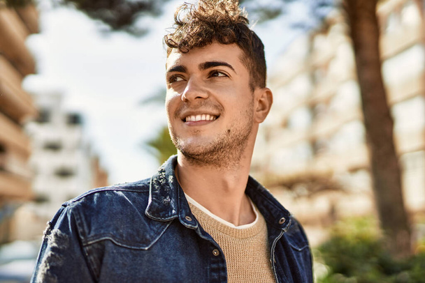 Молодий іспаномовний чоловік усміхається щасливий стоячи в місті
 - Фото, зображення