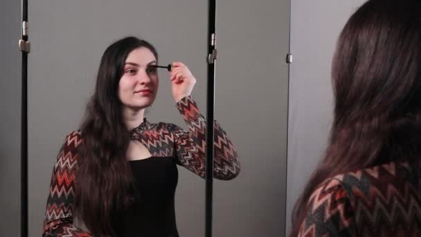 Egy fiatal, gyönyörű barna nő befesti a szemét sminkkel a tükör előtt. Természetes meztelen smink egyedül - Felvétel, videó