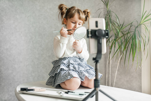 cute caucasian baby girl video blogger, phone on a tripod. - Фото, изображение