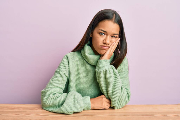 Beautiful hispanic woman wearing casual clothes sitting on the table thinking looking tired and bored with depression problems with crossed arms.  - Foto, Imagen