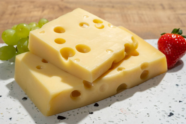 Collezione di formaggi, blocchi di emmentaler formaggio francese con molti fori rotondi a base di latte vaccino da vicino - Foto, immagini