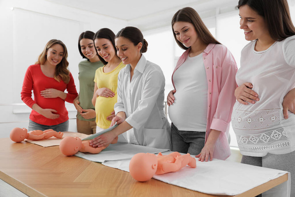 Pregnant women learning how to swaddle baby at courses for expectant mothers indoors - Foto, afbeelding