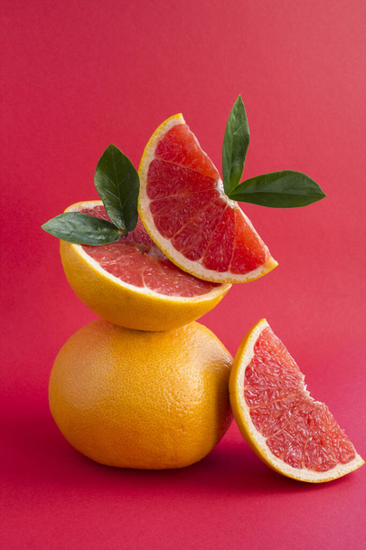 Pyramid of grapefruit in balance on the red background.Close-up. Location vertical. - Photo, Image