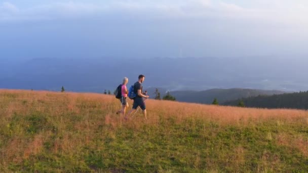 Two young tourists contemplate panorama from mountain. Aerial - Footage, Video