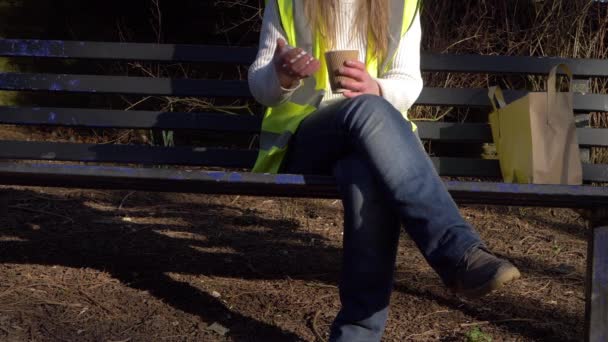 A női munkás kávészünetet tart egy padon. - Felvétel, videó