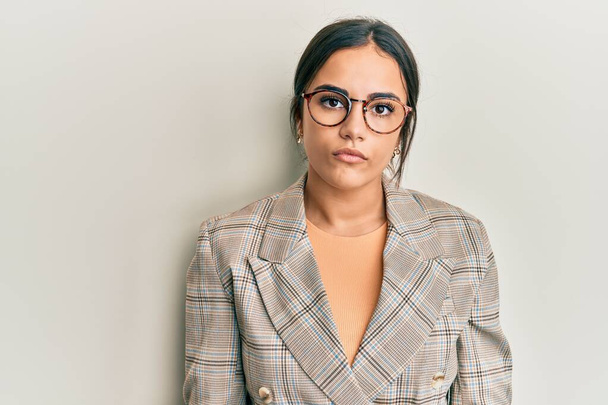 Young brunette woman wearing business jacket and glasses relaxed with serious expression on face. simple and natural looking at the camera.  - Foto, Imagem