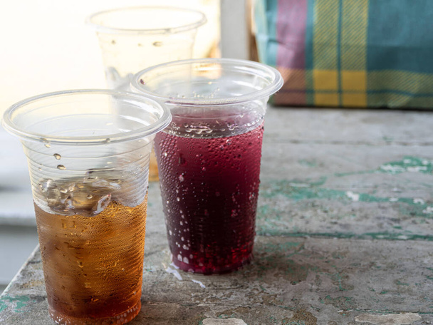 Безалкогольные напитки и лёд в одноразовых пластиковых стаканах - Фото, изображение