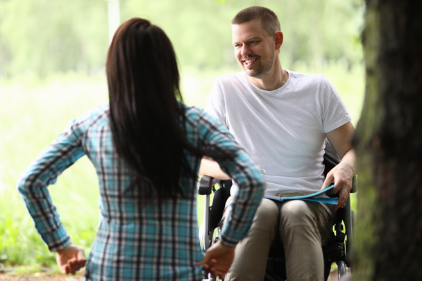 Uomo in sedia a rotelle nel parco comunica con la donna - Foto, immagini