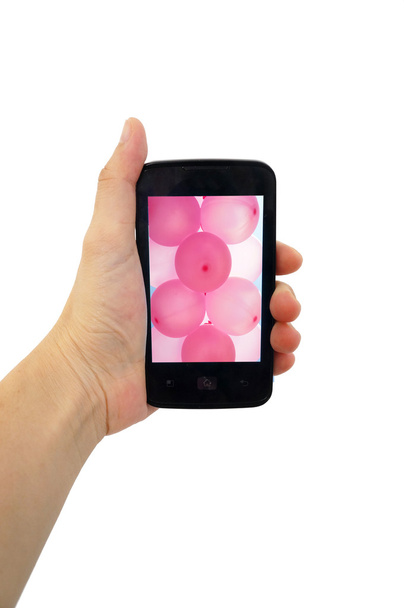 Teléfono móvil en la mano con globo rosa aislado en blanco
 - Foto, Imagen