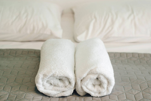 Otel odasındaki yatakta temiz havlular. Beyaz havlu rulolarını kapatın. Havlu otel yatağında yuvarlanıyor.. - Fotoğraf, Görsel