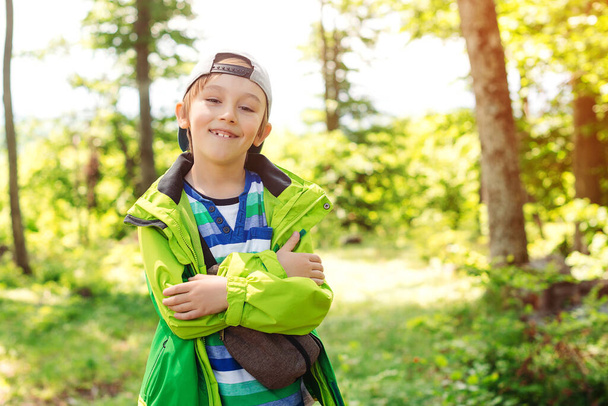 Cute happy boy having fun in forest. Family camping time. Summer vacation, family time on nature. Children hiking in mountains. Happy and healthy childhood. Happy boy enjoying stroll in the forest. - Photo, Image