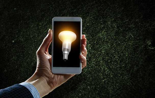 Light bulb on phone screen - Φωτογραφία, εικόνα
