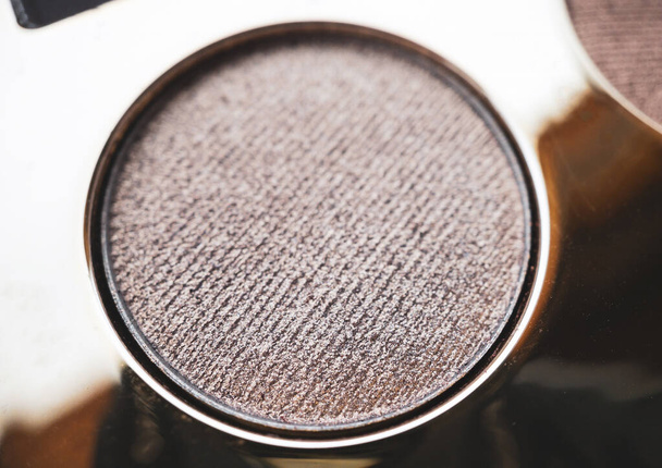 Een close-up van parelmoer glanzende gouden oogschaduw voor het creëren van oogmake-up. Schoonheidsconcept. - Foto, afbeelding